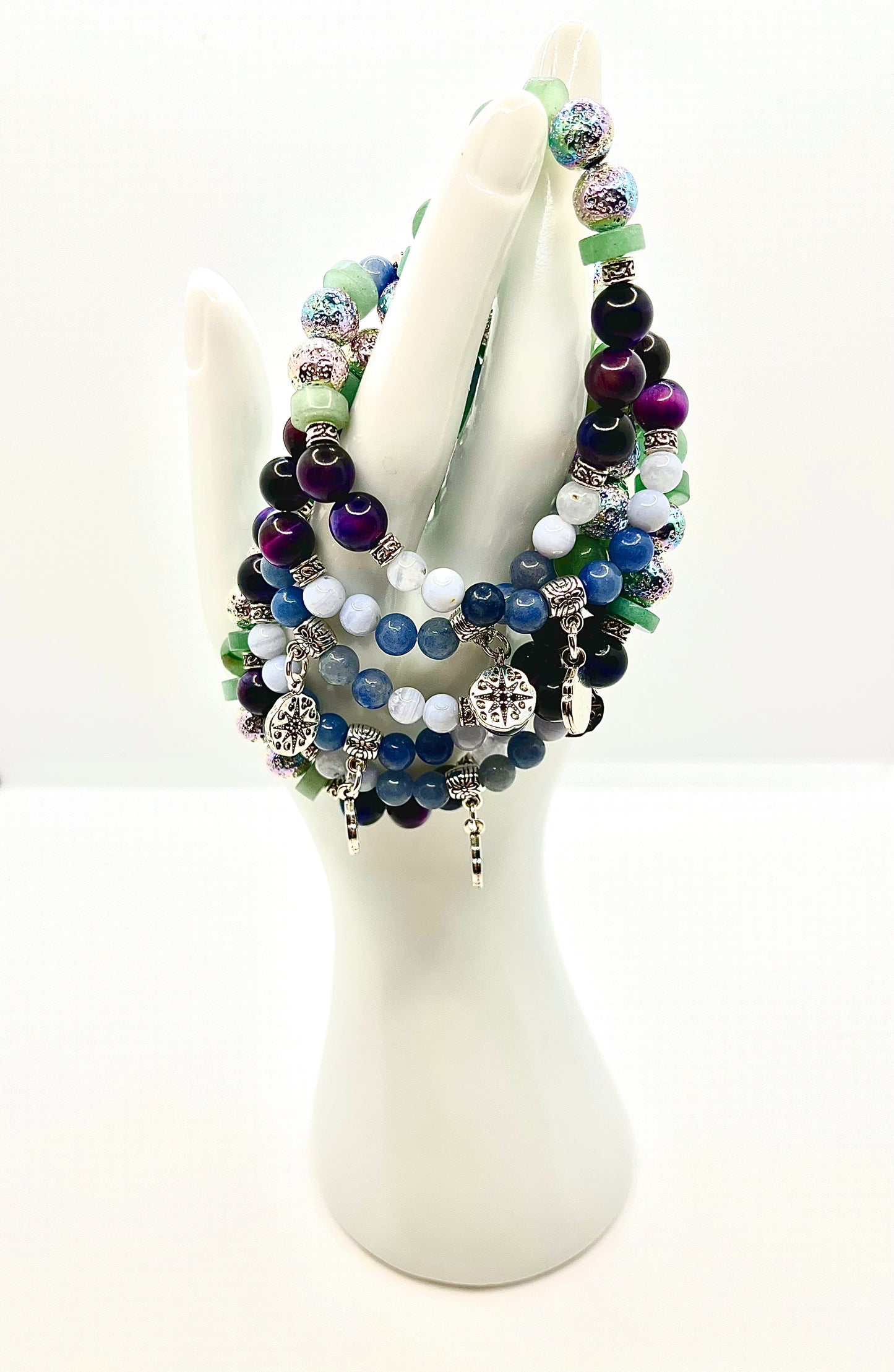 Group of choose your own aventurine bracelets draped on white hand statue