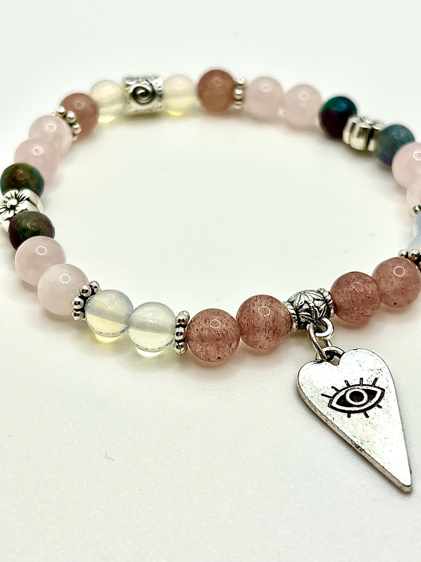 LOVE ME bracelet with green, opalescent, and pink beads, silver flower spacer beads and silver long heart with eye on it