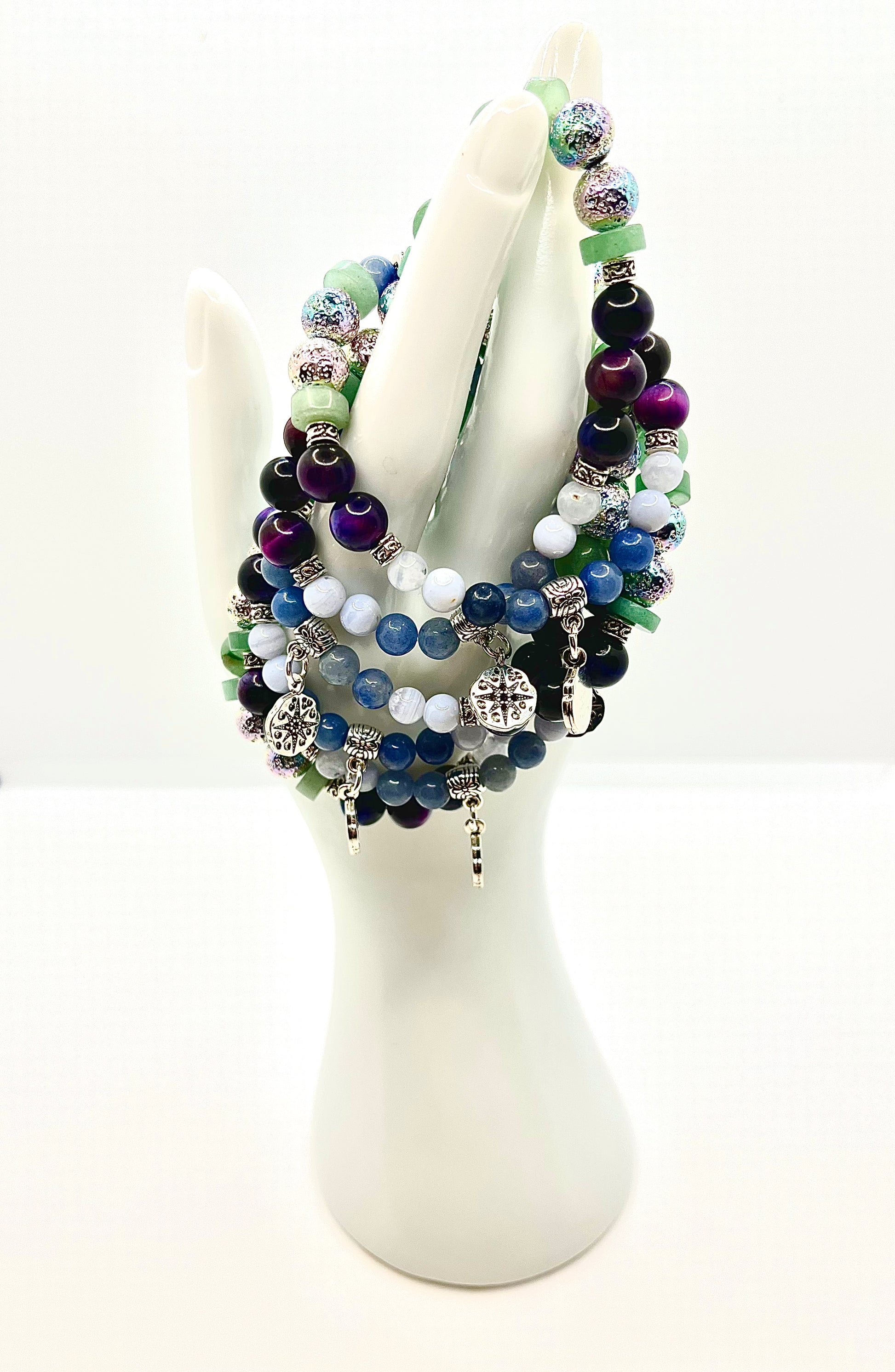 Group of choose your own aventurine bracelets draped on white hand statue 